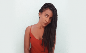 texto sobre tranças e identidade na foto uma mulher negra de cabelos trançados
