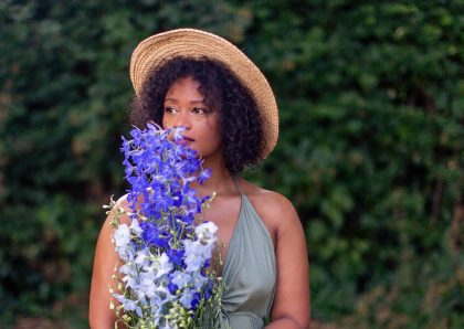 Cabelo crespos e cacheados são mais frágeis que cabelos lisos? imagem de mulher negra com cabelo natural e flores nas mãos